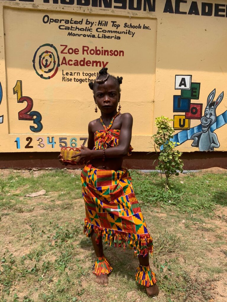 Student at Zoe Robinson Academy wearing traditional clothing and holding a basket on African Costume Day.